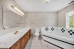 Bathroom with vanity, a garden tub, and light tile patterned floors