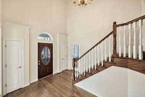 Entrance foyer with dark wood-type flooring, a high ceiling, and hanging lights