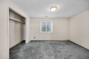 Unfurnished bedroom with carpet flooring, a closet, and a textured ceiling