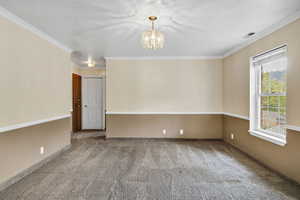 Unfurnished room featuring carpet flooring, suspended lighting, and ornamental molding