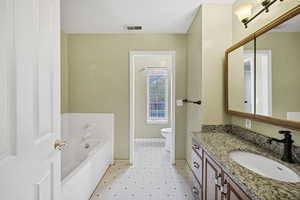 Bathroom with vanity, a garden tub, and light flooring