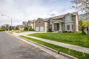 View of front of house featuring driveway, brick siding, a residential view, and a garage