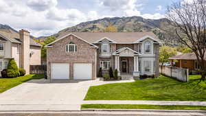 Traditional home featuring brick siding, a mountain view, an attached garage, and driveway