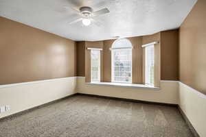 Empty room featuring ceiling fan, carpet floors, and a textured ceiling