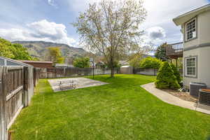 Fenced backyard featuring a patio area, a mountain view, and an outdoor structure