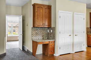 Kitchen featuring backsplash, light stone counters, and wood finish cabinetry
