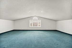 Additional living space with carpet flooring and a textured ceiling