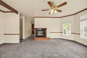 Unfurnished living room with a fireplace, carpet flooring, and a ceiling fan