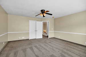 Unfurnished bedroom featuring carpet flooring, a ceiling fan, a closet, and a textured ceiling