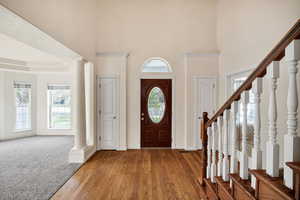 Foyer entrance with decorative columns, hardwood / wood-style flooring, and a high ceiling