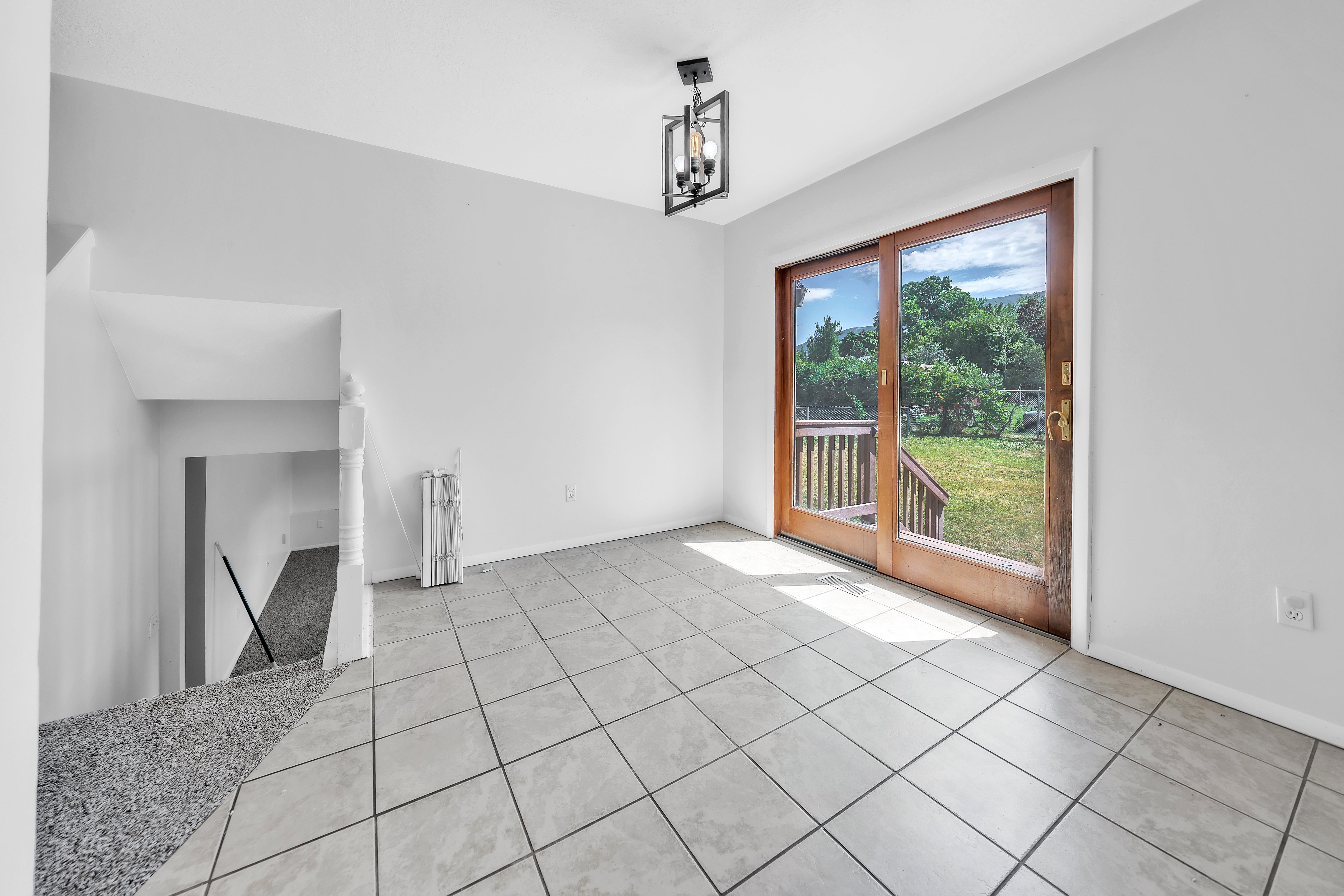 Sliding wood-frame glass doors opening to an exterior wood deck and green space