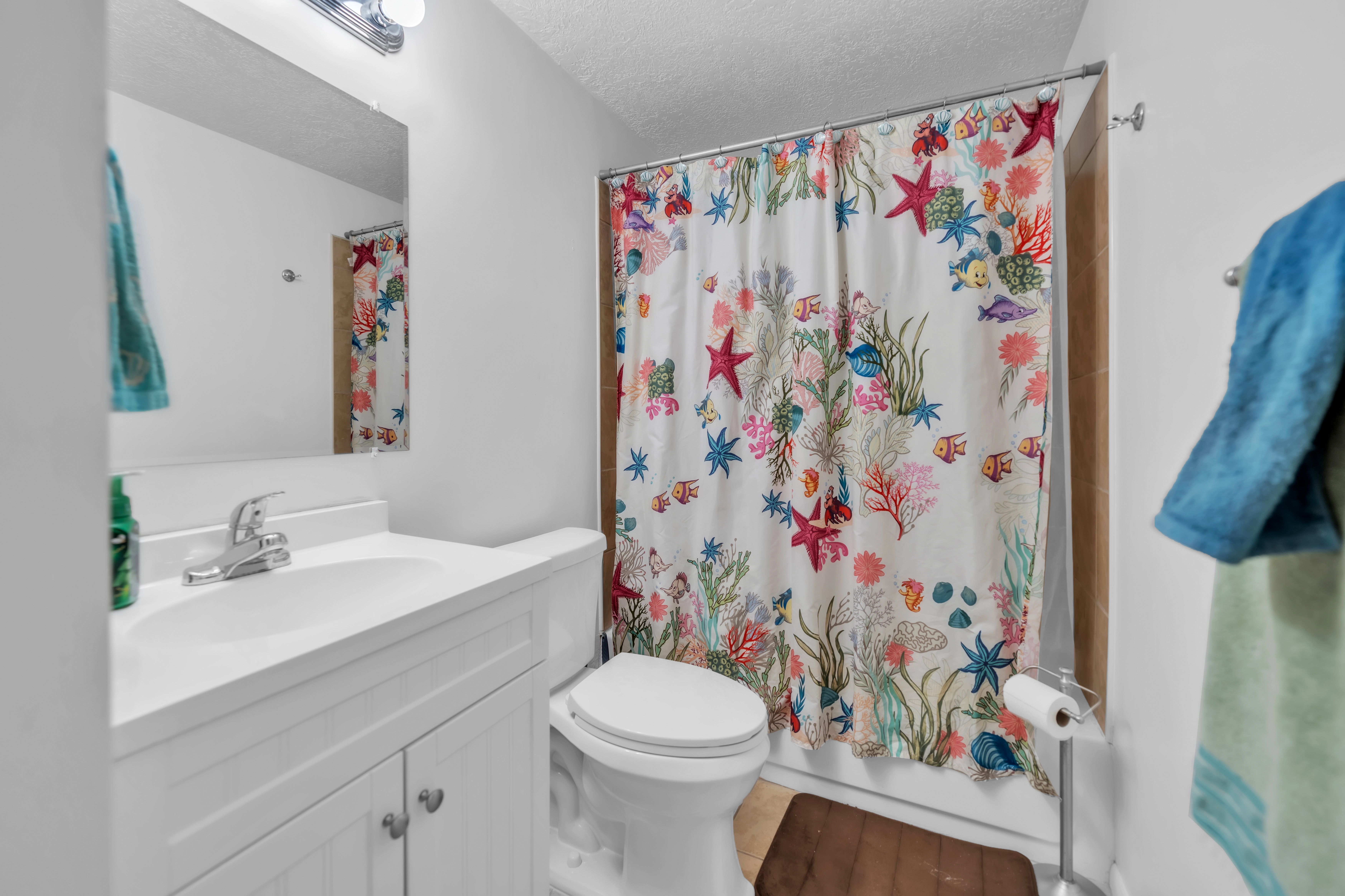Bathroom with vanity, a textured ceiling, and shower / bathtub combination with curtain