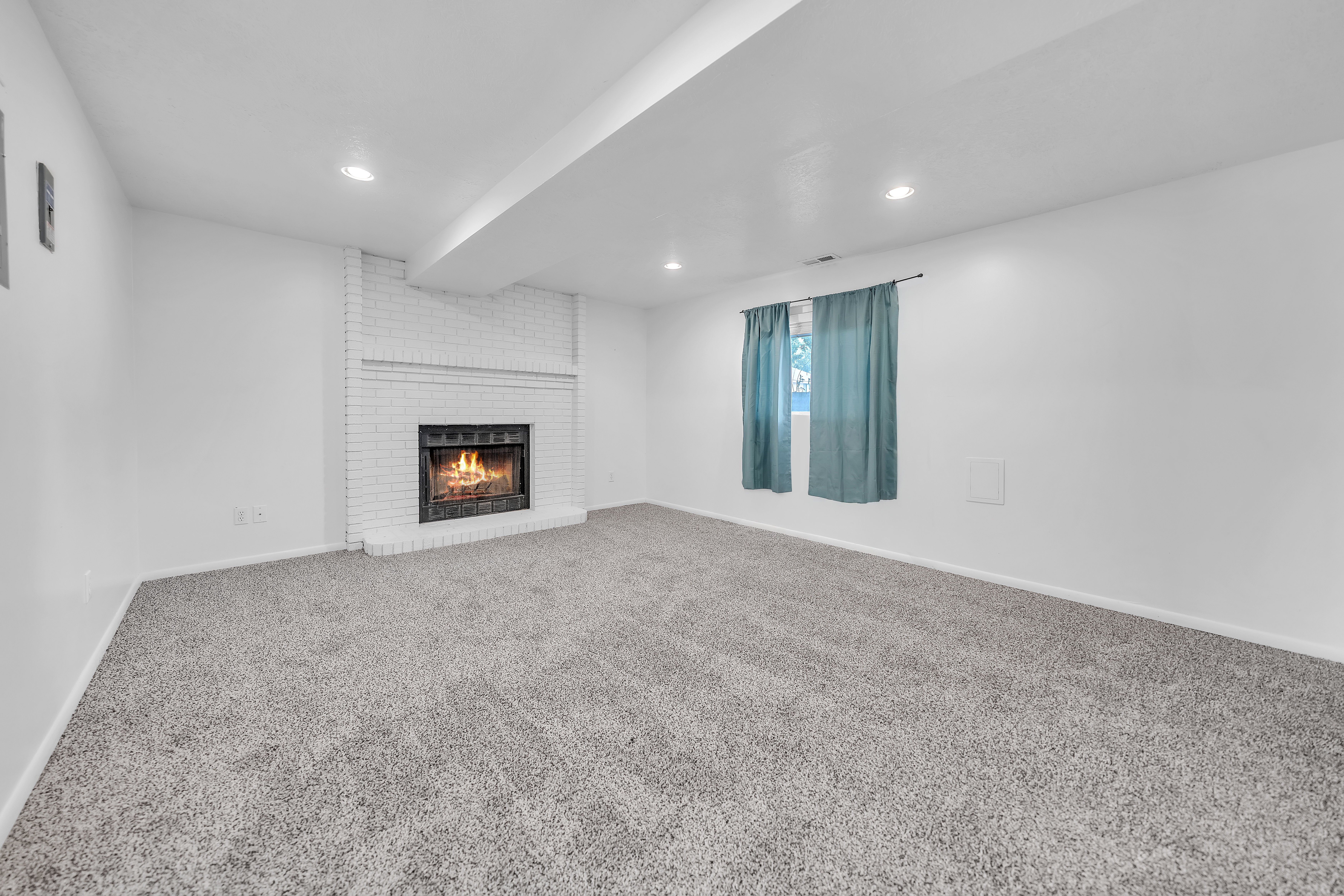 Spacious room featuring a white brick fireplace, recessed lighting, and soft gray carpeting