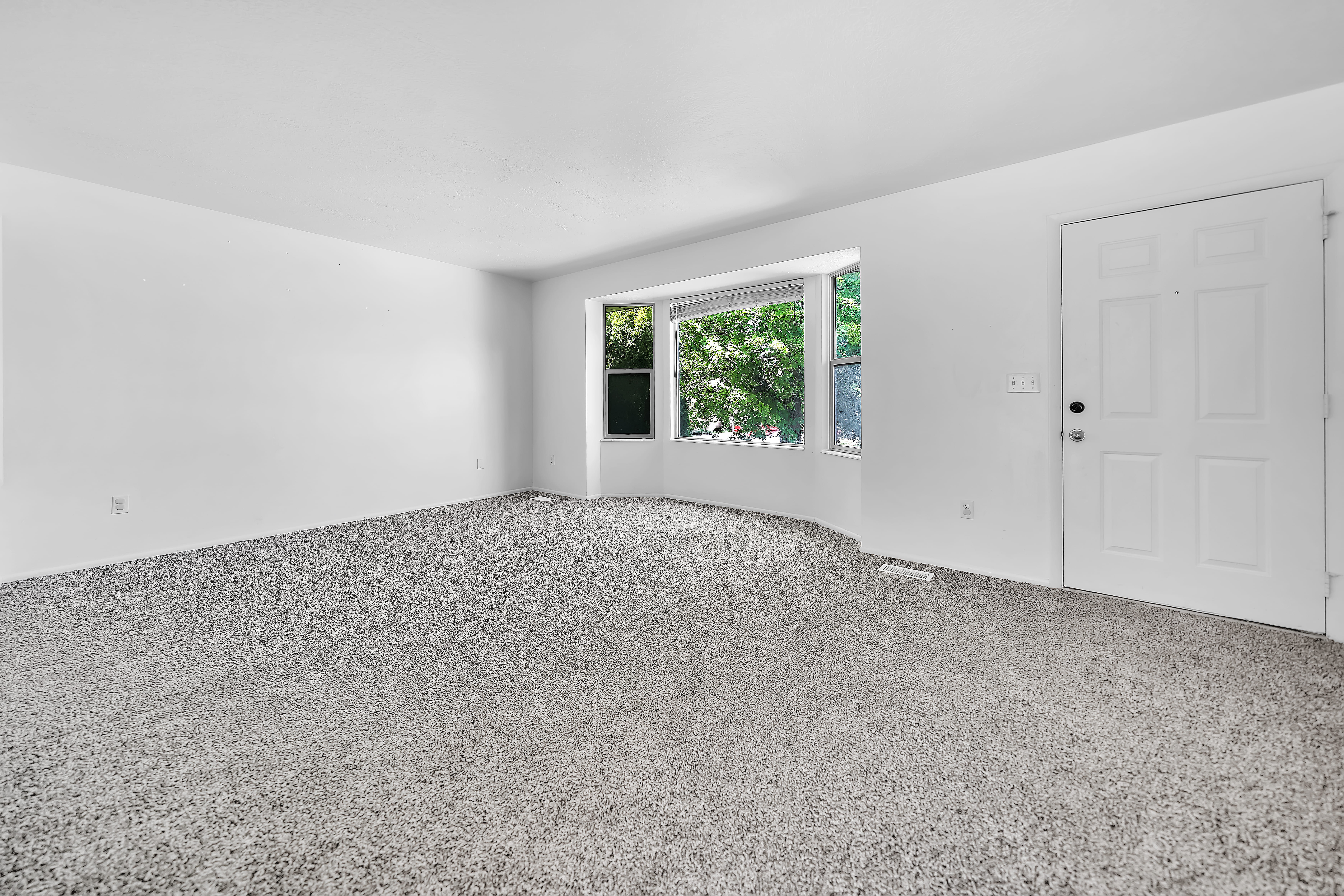 Spacious room featuring light gray carpet flooring and white painted walls