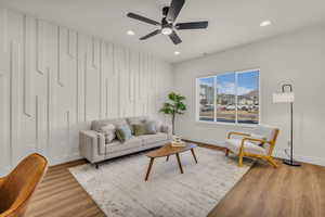 Living area with ceiling fan, light wood finished floors, an accent wall, and recessed lighting