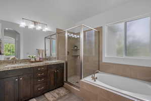 Full bath with double vanity, a stall shower, a bath, and lofted ceiling