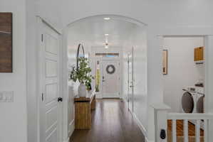 Entrance foyer featuring arched walkways, washer and dryer, and dark wood finished floors