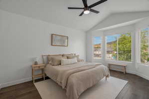 Bedroom with vaulted ceiling, dark wood-style flooring, and a ceiling fan