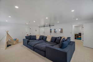 Home theater with a barn door, light carpet, and recessed lighting