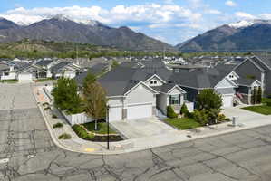 View of front facade with a mountain view, a garage, concrete driveway, and a residential view