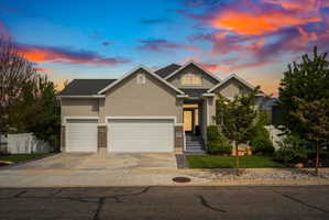 View of front of property with a garage, stucco siding, concrete driveway, and brick siding