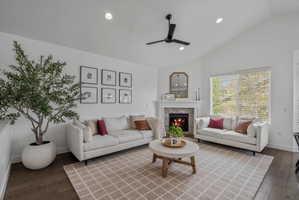 Living room featuring a ceiling fan, a fireplace, dark wood-type flooring, recessed lighting, and lofted ceiling