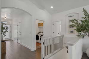 Hallway featuring arched walkways, washer and dryer, dark wood-type flooring, recessed lighting, and vaulted ceiling