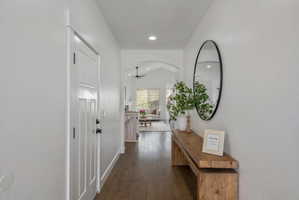 Hallway with lofted ceiling, dark wood-style flooring, recessed lighting, and arched walkways