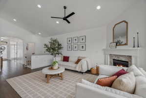 Living area featuring arched walkways, a ceiling fan, wood-type flooring, a fireplace, and recessed lighting