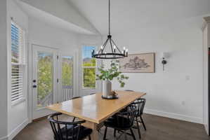 Dining area featuring lofted ceiling, dark wood-style flooring, and hanging lights