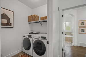 Laundry area with arched walkways, dark wood-style floors, and independent washer and dryer