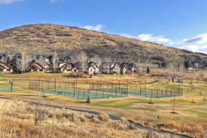 View of tennis court with community basketball court, a lawn, and a residential view