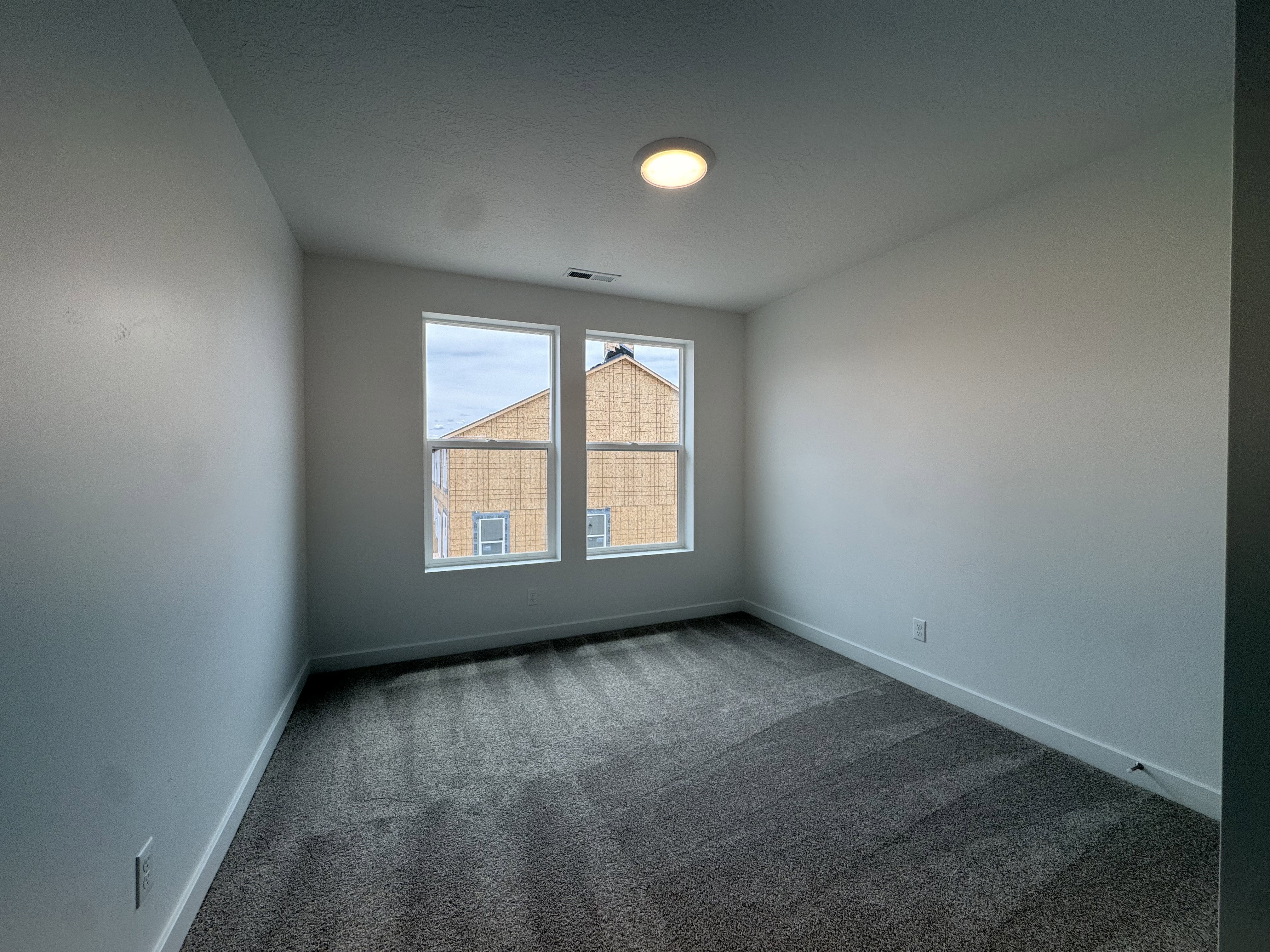 Spare room featuring dark carpet and baseboards