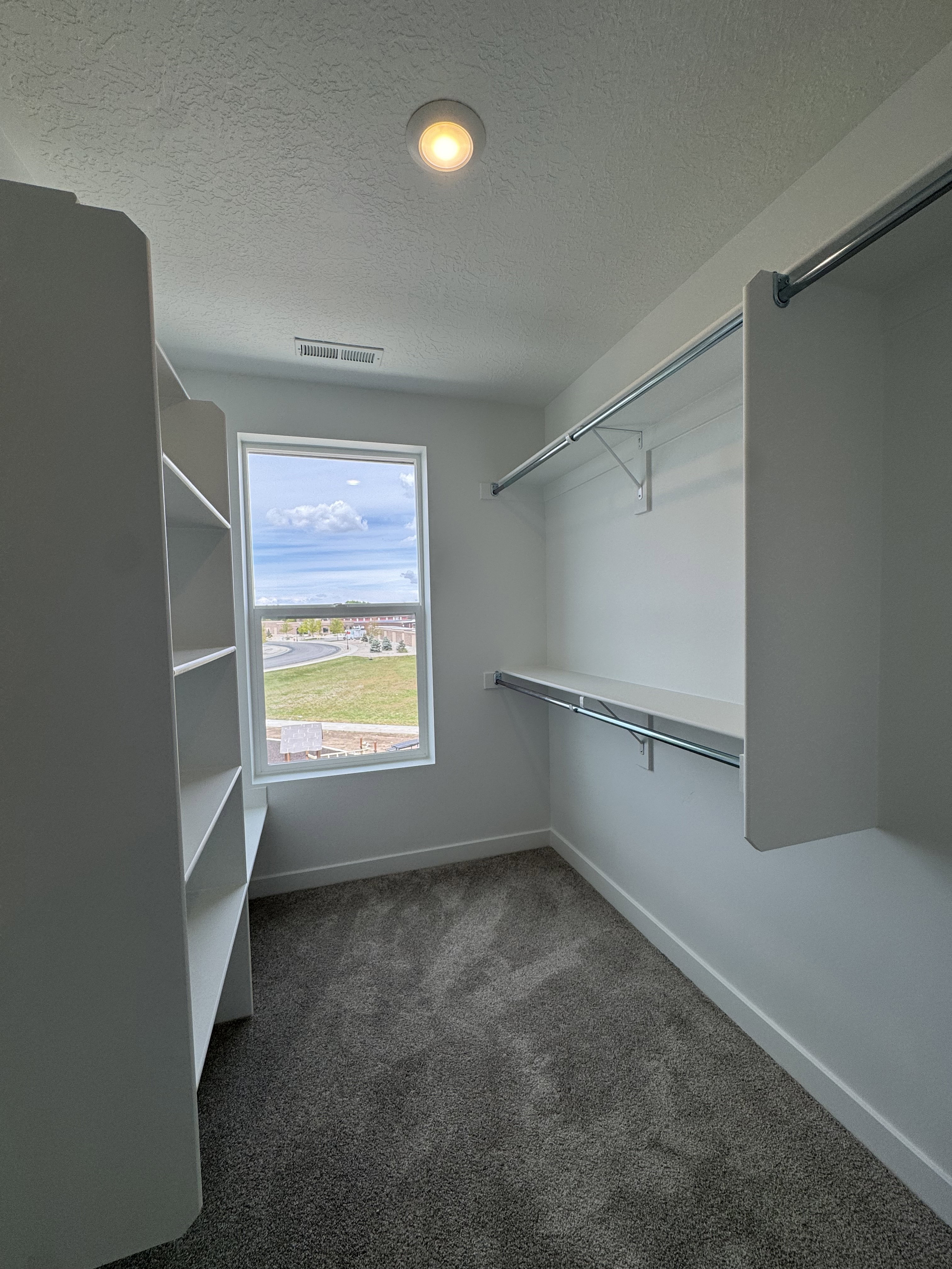 Walk in closet with dark colored carpet