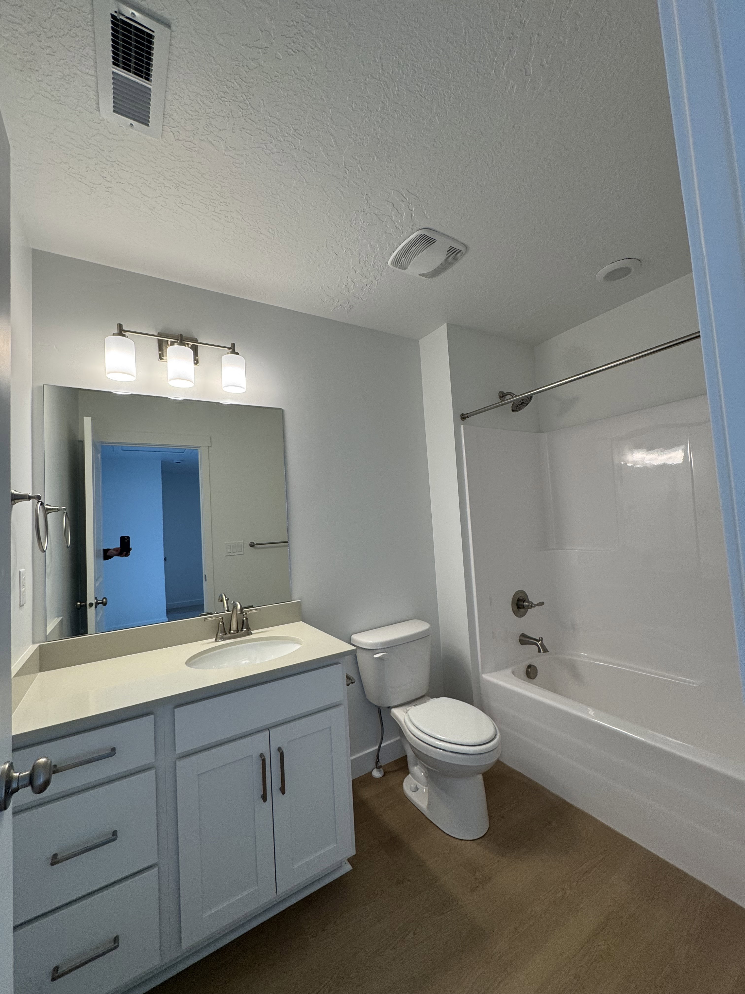 Bathroom featuring vanity, a textured ceiling, dark wood-type flooring, and washtub / shower combination