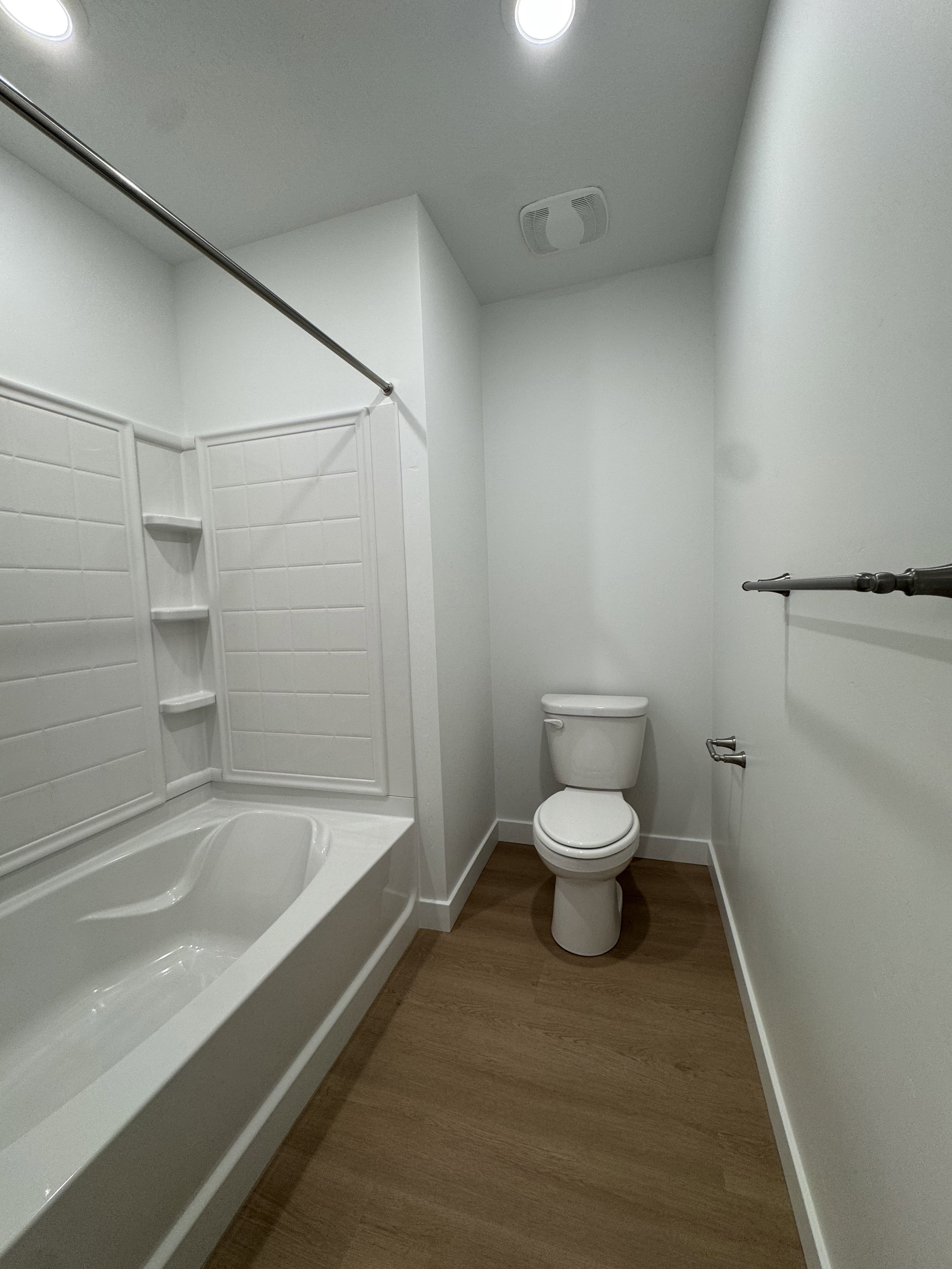 Bathroom with shower / washtub combination, dark wood-type flooring, and recessed lighting