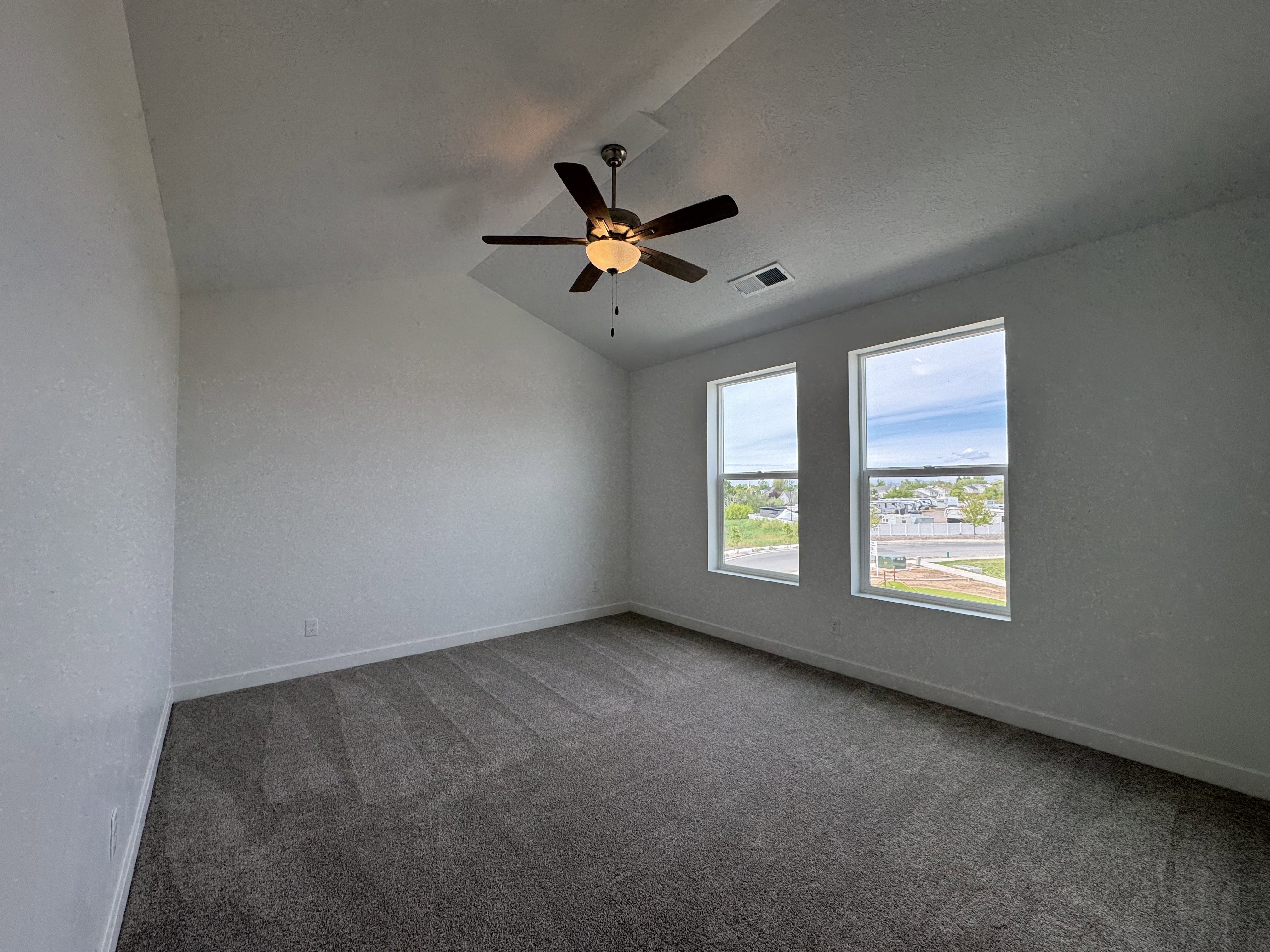 Carpeted spare room with vaulted ceiling and a ceiling fan