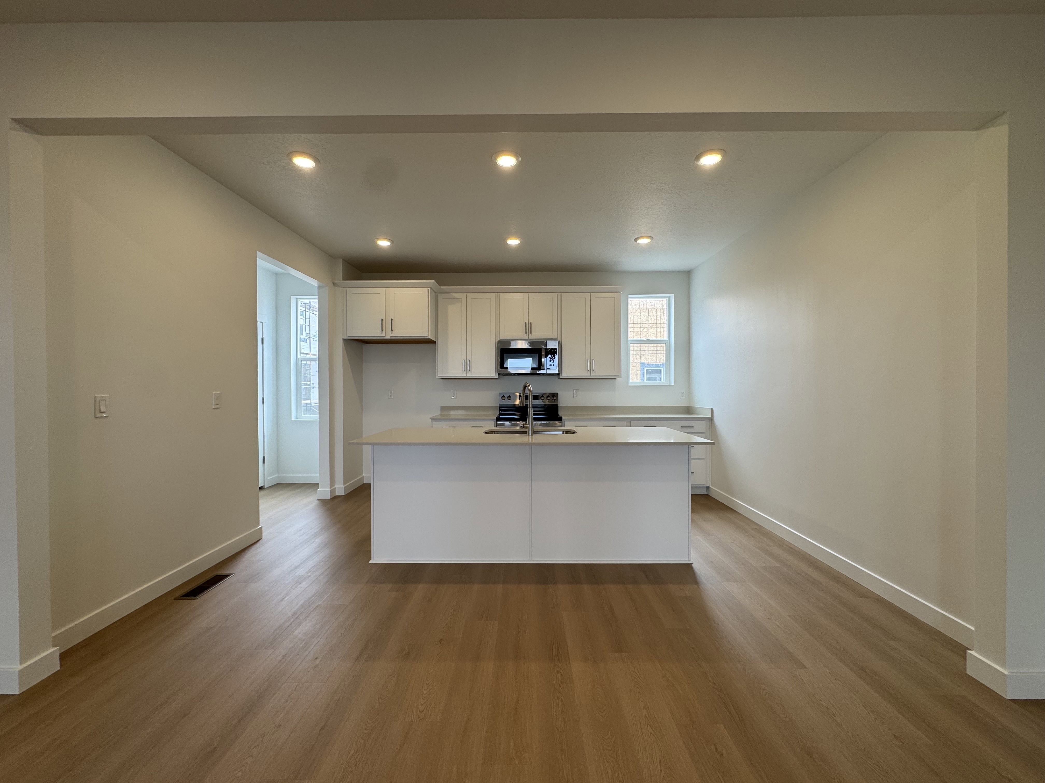 Kitchen featuring white cabinets, recessed lighting, an island with sink, dark wood-type flooring, and range with electric stovetop
