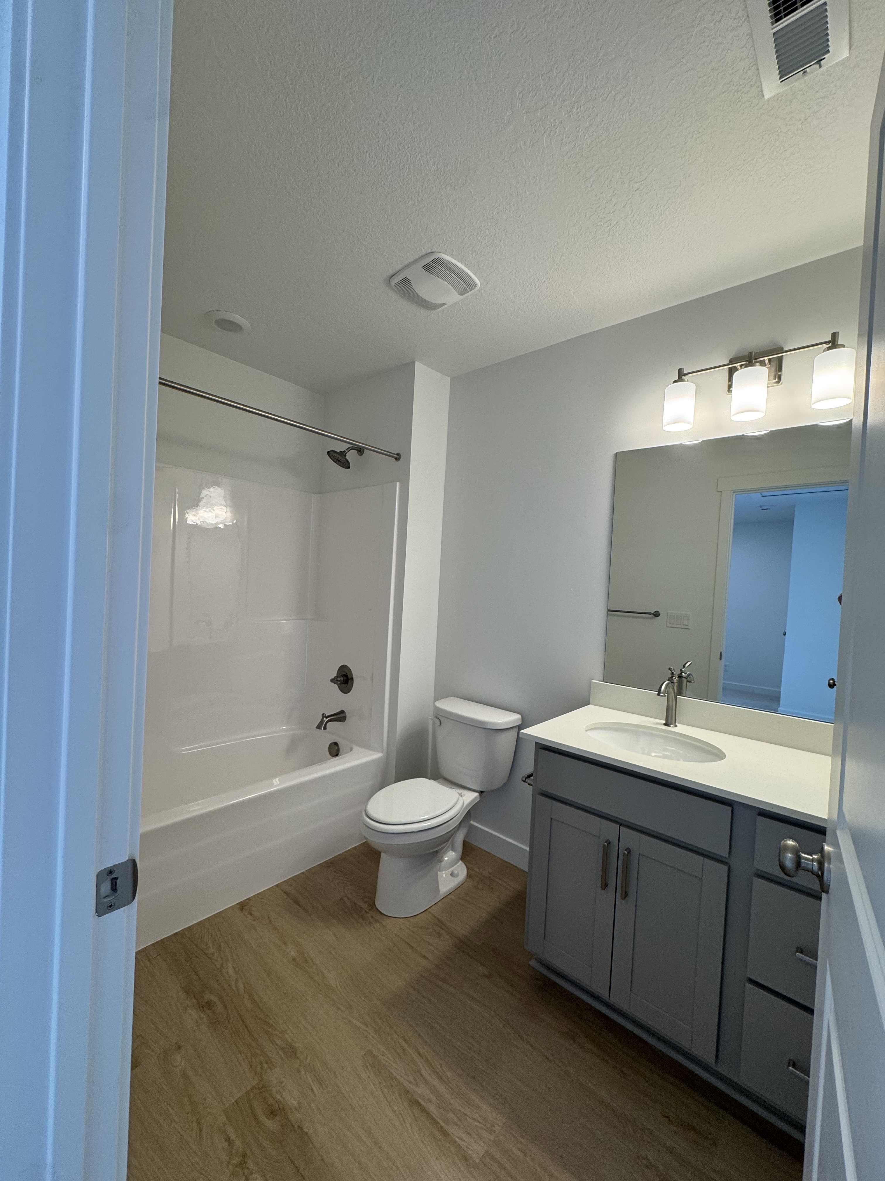 Full bathroom with vanity, dark wood-style flooring,  shower combination, and a textured ceiling