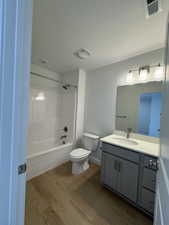 Full bathroom with vanity, dark wood-style flooring,  shower combination, and a textured ceiling