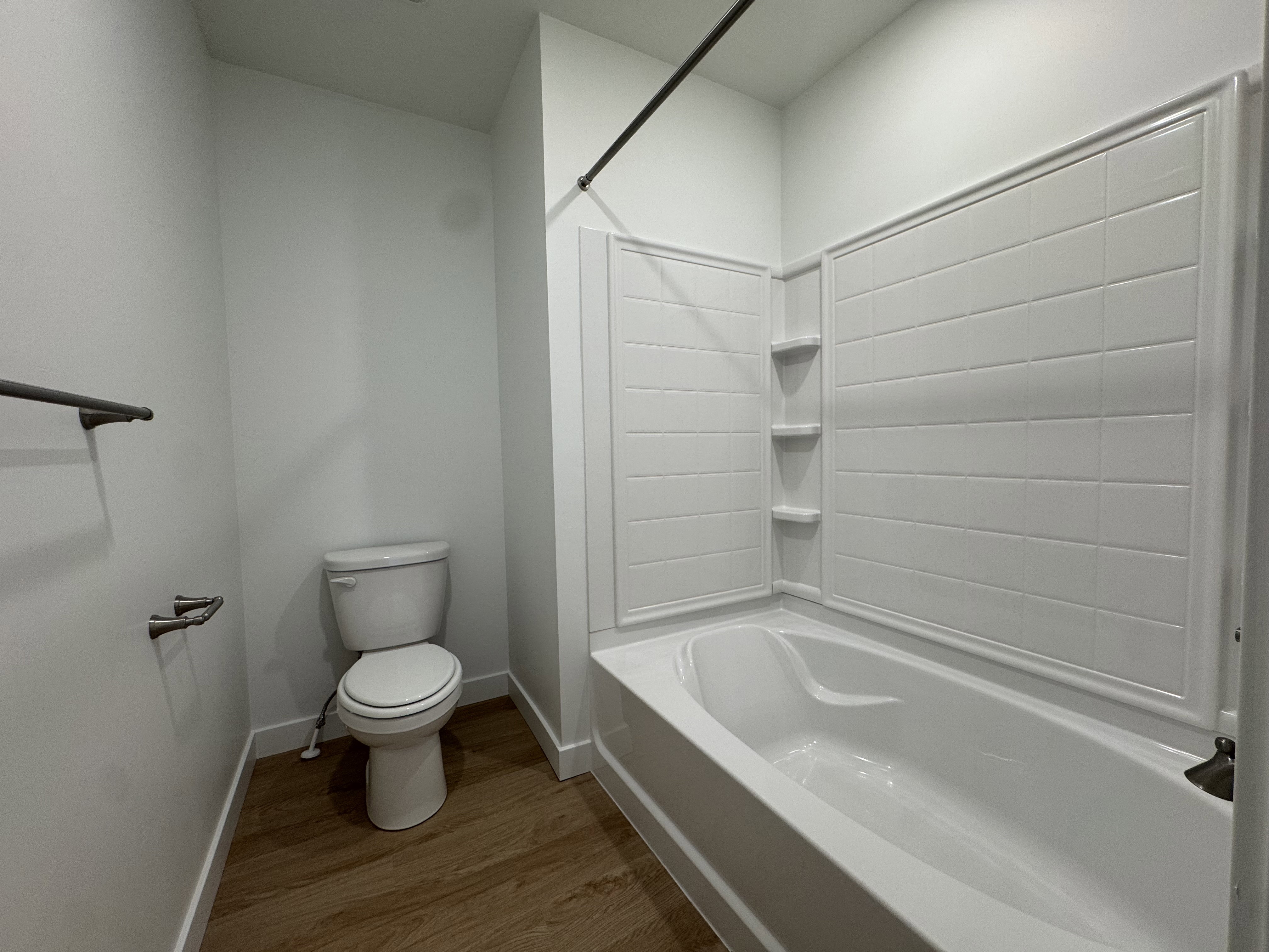 Bathroom with shower / bath combination and dark wood-style floors