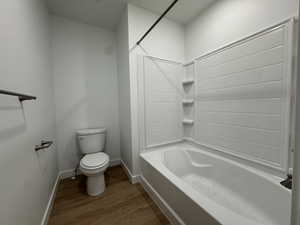 Bathroom with shower / bath combination and dark wood-style floors