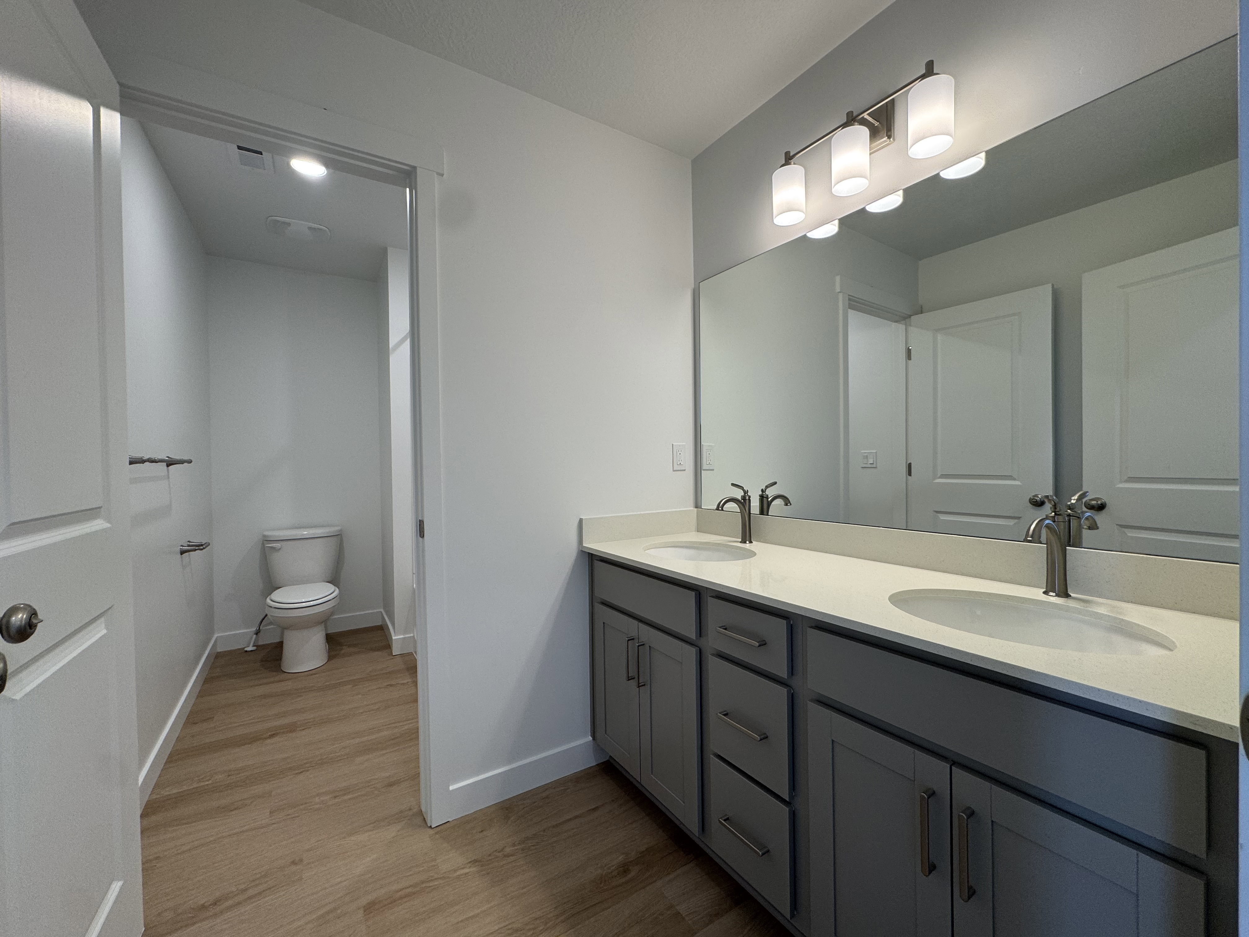 Full bath with double vanity and light wood finished floors