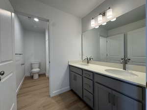Full bath with double vanity and light wood finished floors