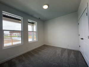 Unfurnished bedroom featuring a closet, dark carpet, and a textured ceiling