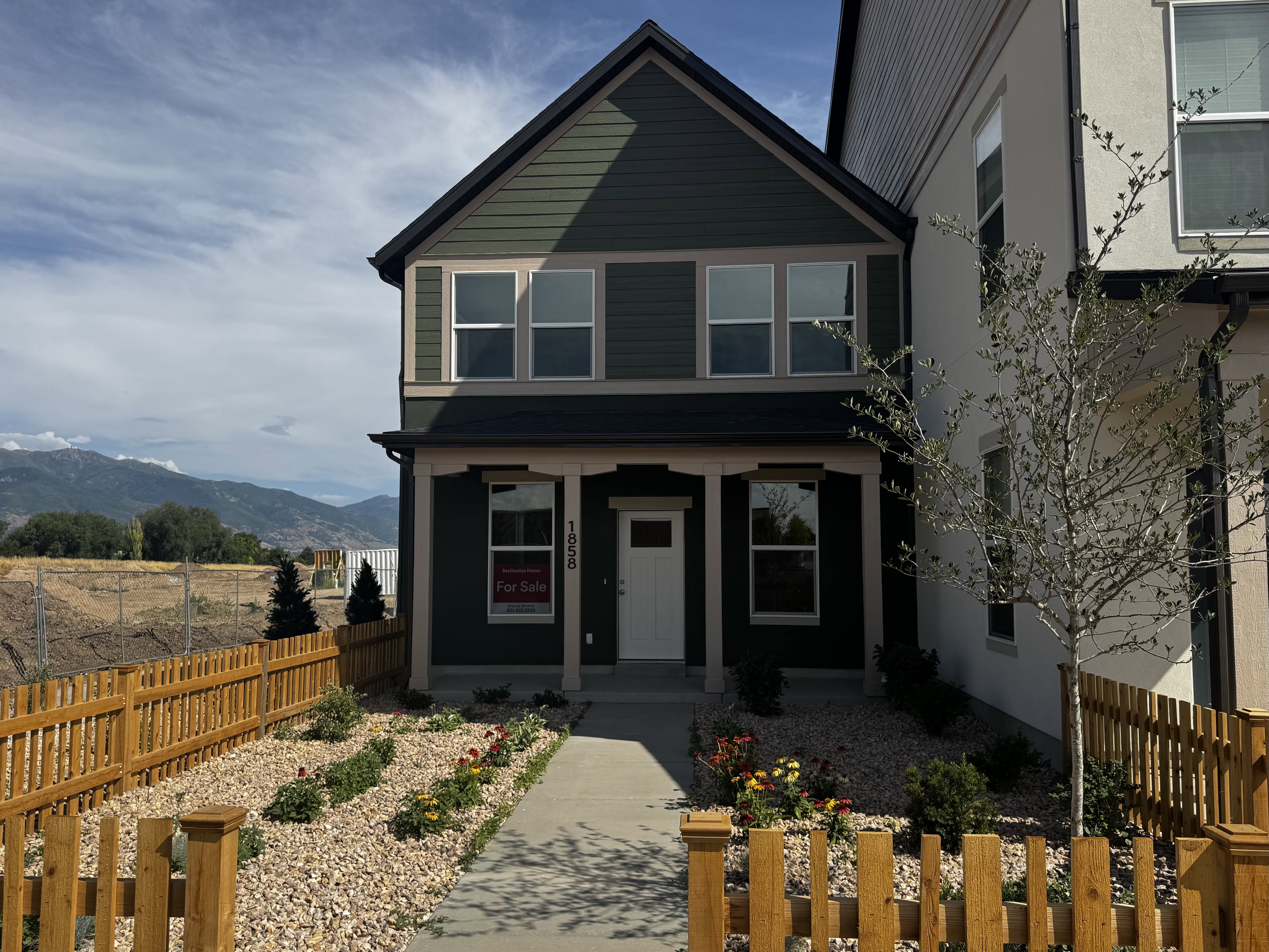 Two-story residence featuring dark green siding with black trim, a white front door, and a covered porch entry