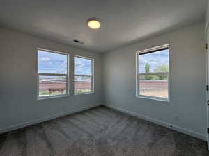Unfurnished room featuring dark carpet and a textured ceiling