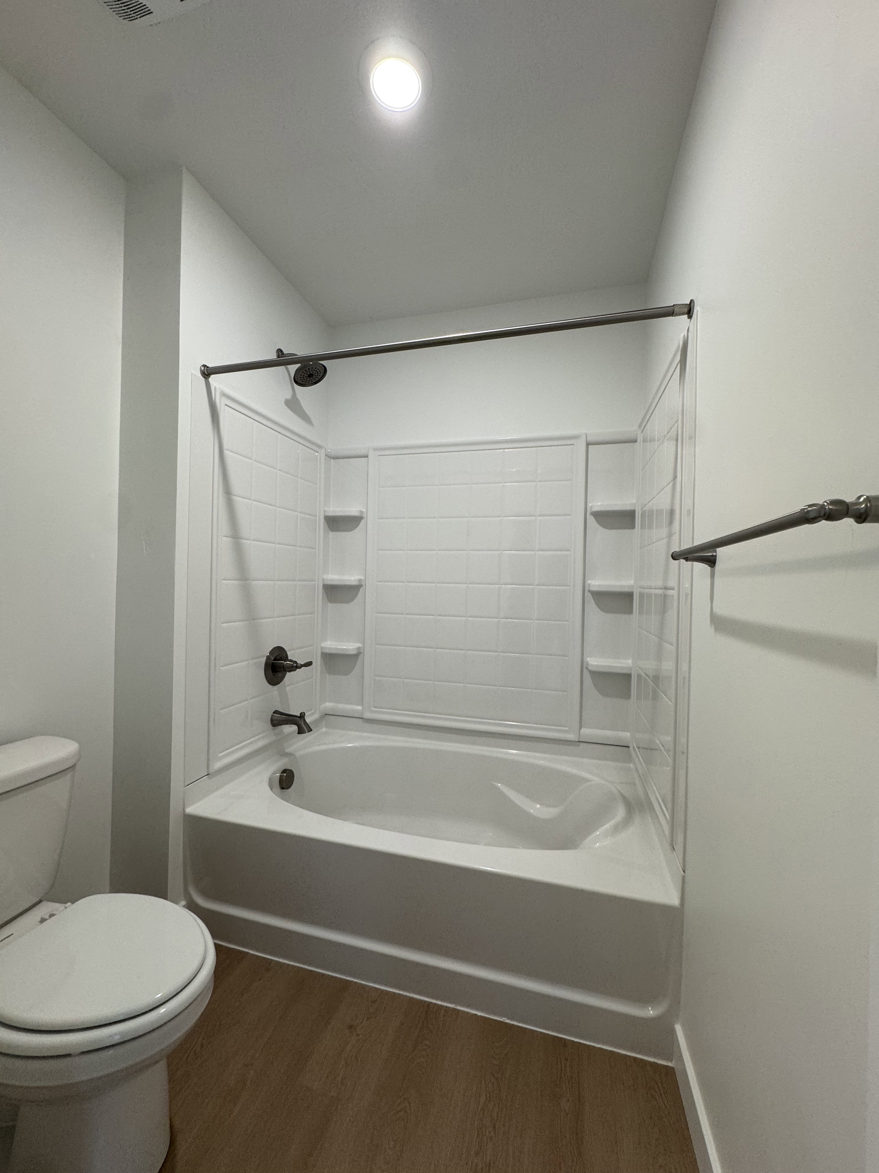 Bathroom featuring dark wood-style flooring and washtub / shower combination