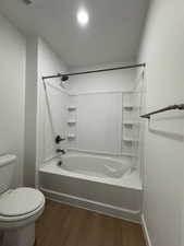 Bathroom featuring dark wood-style flooring and washtub / shower combination