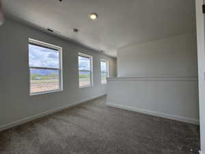 Unfurnished room with dark carpet and a textured ceiling